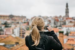 A tourist girl at the observation deck takes pictures of a beautiful view of the city in Porto in Portugal on a mobile stock photo A tourist girl at the observation deck takes pictures of a beautiful view of the city in Porto in Portugal on a mobile stock photo