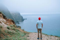 Tourist in a red cap stands on a cliff overlooking the sea. stock image Tourist in a red cap stands on a cliff overlooking the sea. stock image
