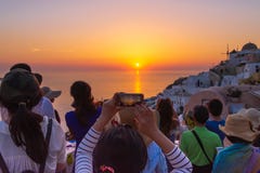 Tourist taking picture of beautiful sunset in Santorini, Greece