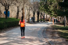 Touriste de fille dans le T-shirt orange marchant avec le sac à dos en parc sur la route images libres de droits Touriste de fille dans le T-shirt orange marchant avec le sac à dos en parc sur la route images libres de droits