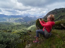 Touriste de jeune femme avec le sac à dos se reposant sur le bord du ` s de falaise et merci images libres de droits Touriste de jeune femme avec le sac à dos se reposant sur le bord du ` s de falaise et merci images libres de droits