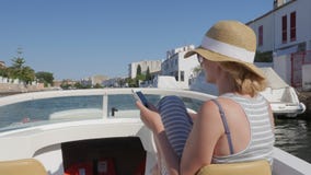 Touristisches Segeln der Frau auf einem kleinen Boot auf dem Kanal Benutzen Sie Handys Empuriabrava, Spanien stock video footage Touristisches Segeln der Frau auf einem kleinen Boot auf dem Kanal Benutzen Sie Handys Empuriabrava, Spanien stock video footage