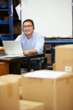 Trabajador en las auriculares de Warehouse y ordenador portátil con que llevan fotos de archivo libres de regalías Trabajador en las auriculares de Warehouse y ordenador portátil con que llevan fotos de archivo libres de regalías