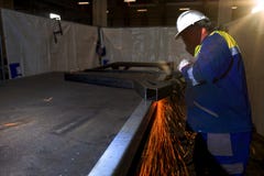 Trabajador que usa la amoladora de ?ngulo en emplazamiento de la obra imagen de archivo Trabajador que usa la amoladora de ?ngulo en emplazamiento de la obra imagen de archivo