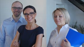 Trabajo en equipo de la gente joven en la oficina que mira a la cámara y a la sonrisa almacen de video Trabajo en equipo de la gente joven en la oficina que mira a la cámara y a la sonrisa almacen de video