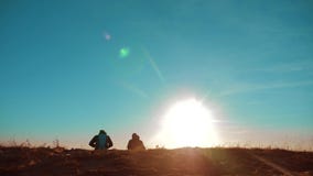 Trabajo en equipo dos hombres y perros de los caminantes de los turistas con las mochilas que caminan en la puesta del sol para i metrajes Trabajo en equipo dos hombres y perros de los caminantes de los turistas con las mochilas que caminan en la puesta del sol para i metrajes