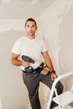 Trabalhador da indústria da construção civil com ferramentas e broca que renova a casa no canteiro de obras fotografia de stock royalty free Trabalhador da indústria da construção civil com ferramentas e broca que renova a casa no canteiro de obras fotografia de stock royalty free