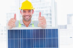 Trabalhador manual de sorriso com painel solar que gesticula os polegares acima fotografia de stock Trabalhador manual de sorriso com painel solar que gesticula os polegares acima fotografia de stock