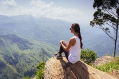 Tracking tourist adventure. Woman sitting on the top of Ella rock, Sri Lanka.