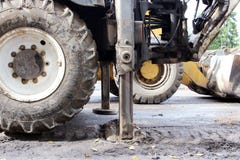Tractor strong outrigger stabilizing legs extended to stabilize and steady state when digging the soil under the road repair. Royalty Free Stock Photo Tractor strong outrigger stabilizing legs extended to stabilize and steady state when digging the soil under the road repair. Royalty Free Stock Photo