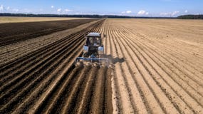 Tractor - vista a?rea de un tractor en el trabajo - que cultiva un campo en primavera con el cielo azul - maquinaria agr?cola imágenes de archivo libres de regalías Tractor - vista a?rea de un tractor en el trabajo - que cultiva un campo en primavera con el cielo azul - maquinaria agr?cola imágenes de archivo libres de regalías