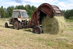 Tractor With Round Baler Collects The Hay To Hayfield. Royalty Free Stock Photo Tractor With Round Baler Collects The Hay To Hayfield. Royalty Free Stock Photo