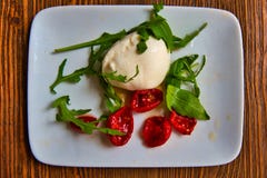 Traditional Apulian food. Burrata with confit tomatoes and rocket. royalty free stock photo Traditional Apulian food. Burrata with confit tomatoes and rocket. royalty free stock photo