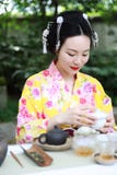 Traditional Asian Japanese beautiful Geisha woman wears kimono show tea art ceremony drink tea in a summer spring outdorr garden Stock Photo Traditional Asian Japanese beautiful Geisha woman wears kimono show tea art ceremony drink tea in a summer spring outdorr garden Stock Photo