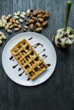 Traditional Belgian waffles covered in chocolate on a dark wooden background. Tasty breakfast . Decorated with raschlichnymi nuts stock photos Traditional Belgian waffles covered in chocolate on a dark wooden background. Tasty breakfast . Decorated with raschlichnymi nuts stock photos