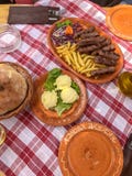 Traditional Food from Montenegro cevapi, butter, and bread on a red plaid tablecloth and ceramic plates stock photography Traditional Food from Montenegro cevapi, butter, and bread on a red plaid tablecloth and ceramic plates stock photography