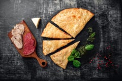 Traditional Italian pizza calzone with ingredients on a stone and dark wooden scratched background royalty free stock image Traditional Italian pizza calzone with ingredients on a stone and dark wooden scratched background royalty free stock image