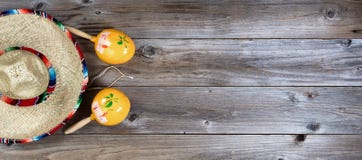 Traditional maracas and large sombrero for Cinco de Mayo holiday. Flat lay view of yellow maracas and large sombrero on rustic red wooden boards for Cinco de Traditional maracas and large sombrero for Cinco de Mayo holiday. Flat lay view of yellow maracas and large sombrero on rustic red wooden boards for Cinco de