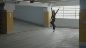 Tragendes Gesellschaftsanzugspringen der jungen attraktiven Geschäftsfrau und lustiges Tanzen in einem Untertageparkplatz auf ihr stock video footage Tragendes Gesellschaftsanzugspringen der jungen attraktiven Geschäftsfrau und lustiges Tanzen in einem Untertageparkplatz auf ihr stock video footage