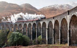 Train de vapeur sur un pont arqué à Hogwarts dans les montagnes photographie stock libre de droits Train de vapeur sur un pont arqué à Hogwarts dans les montagnes photographie stock libre de droits