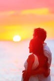 Tramonto di sorveglianza delle coppie felici alla vacanza della spiaggia fotografie stock Tramonto di sorveglianza delle coppie felici alla vacanza della spiaggia fotografie stock