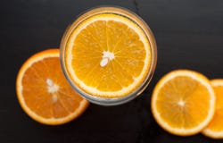 Tranche orange dans le verre, la vue à partir du dessus, sur un fond en bois noir, plan rapproché, image libre de droits Tranche orange dans le verre, la vue à partir du dessus, sur un fond en bois noir, plan rapproché, image libre de droits