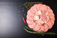 Tranches de saucisse et de lard sur une planche à découper ronde avec le rosema photo libre de droits Tranches de saucisse et de lard sur une planche à découper ronde avec le rosema photo libre de droits