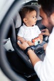 Trasporto della famiglia, concetto di stile di vita - padre che mette bambino nel sedile del bambino, cintura di sicurezza di fis fotografia stock Trasporto della famiglia, concetto di stile di vita - padre che mette bambino nel sedile del bambino, cintura di sicurezza di fis fotografia stock