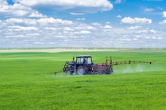 Trator que pulveriza um campo de exploração agrícola foto de stock Trator que pulveriza um campo de exploração agrícola foto de stock