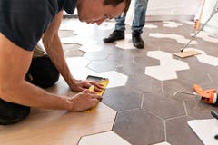 Travailleur de sexe masculin installant le nouveau plancher en stratifié en bois La combinaison des panneaux en bois du stratifié photos stock Travailleur de sexe masculin installant le nouveau plancher en stratifié en bois La combinaison des panneaux en bois du stratifié photos stock