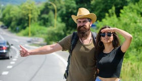 Travellers try to stop car. Couple hitchhikers travelling summer sunny day. Couple travelers man and girl hitchhiking at Stock Photo Travellers try to stop car. Couple hitchhikers travelling summer sunny day. Couple travelers man and girl hitchhiking at Stock Photo