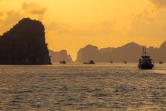 Travesía de la nave en la bahía larga en la puesta del sol, Vietnam de la ha foto de archivo libre de regalías Travesía de la nave en la bahía larga en la puesta del sol, Vietnam de la ha foto de archivo libre de regalías