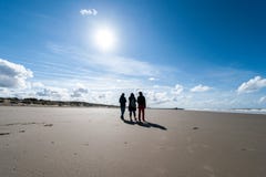 Tre amici che camminano sulla spiaggia nell'inverno fotografie stock Tre amici che camminano sulla spiaggia nell'inverno fotografie stock