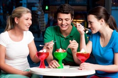 Tre amici che godono tentando dessert Immagine Stock Tre amici che godono tentando dessert Immagine Stock