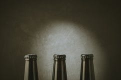 tre bottiglie nere di birra su un fondo scuro con luce/tre bottiglie nere di birra su un fondo scuro con luce copia immagini stock libere da diritti tre bottiglie nere di birra su un fondo scuro con luce/tre bottiglie nere di birra su un fondo scuro con luce copia immagini stock libere da diritti