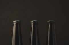tre colli con un tappo delle bottiglie di birra/tre colli con un tappo delle bottiglie di birra su un fondo scuro fotografia stock tre colli con un tappo delle bottiglie di birra/tre colli con un tappo delle bottiglie di birra su un fondo scuro fotografia stock