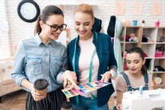 Tre donne alla fabbrica dell'indumento Stanno esaminando i modelli di colore per il nuovo vestito immagini stock libere da diritti Tre donne alla fabbrica dell'indumento Stanno esaminando i modelli di colore per il nuovo vestito immagini stock libere da diritti