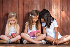 Tre flickor som spelar med minnestavlan och, ilar telefonen. arkivbild Tre flickor som spelar med minnestavlan och, ilar telefonen. arkivbild