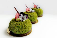 Tre gröna texturerade pistaschefterrätter med ätliga penséblommor och torkade jordgubbar royaltyfri foto Tre gröna texturerade pistaschefterrätter med ätliga penséblommor och torkade jordgubbar royaltyfri foto