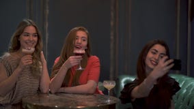 Tre gulliga flickor sitter i ett kafé eller en restaurang som poserar och tar beautifully en fotoselfie för sociala nätverk Tre gulliga flickor sitter i ett kafé eller en restaurang som poserar och tar beautifully en fotoselfie för sociala nätverk