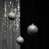 Tre palle d'argento d'attaccatura di Natale su fondo scuro e d'argento immagini stock Tre palle d'argento d'attaccatura di Natale su fondo scuro e d'argento immagini stock