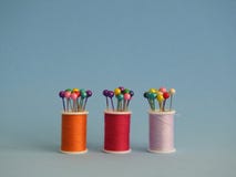 Tre piccole bobine del filato cucirino riempite di perni di cucitura colorati fotografia stock libera da diritti Tre piccole bobine del filato cucirino riempite di perni di cucitura colorati fotografia stock libera da diritti