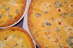 Tre pizze con quattro generi di formaggio della dimensione differente su un fondo scuro fotografia stock libera da diritti Tre pizze con quattro generi di formaggio della dimensione differente su un fondo scuro fotografia stock libera da diritti