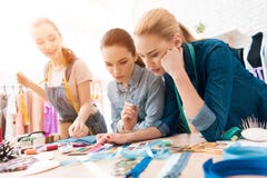 Tre ragazze alla fabbrica dell'indumento Stanno scegliendo i colori per il nuovo vestito immagine stock Tre ragazze alla fabbrica dell'indumento Stanno scegliendo i colori per il nuovo vestito immagine stock