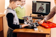 Tre smarta pojkar gör robotar från den robotic konstruktörn på skrivbordet med datoren i skolan av robotteknik royaltyfria foton Tre smarta pojkar gör robotar från den robotic konstruktörn på skrivbordet med datoren i skolan av robotteknik royaltyfria foton