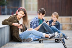 Tre tonåringar med smartphones i utomhus arkivfoton Tre tonåringar med smartphones i utomhus arkivfoton