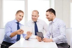 Tre uomini d'affari sorridenti con il pc della compressa in ufficio Immagine Stock Tre uomini d'affari sorridenti con il pc della compressa in ufficio Immagine Stock