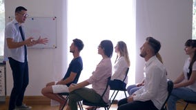Treinamento do negócio, treinador que explica o desenvolvimento de ideias do negócio para colegas na aprendizagem ativa no seminá video estoque Treinamento do negócio, treinador que explica o desenvolvimento de ideias do negócio para colegas na aprendizagem ativa no seminá video estoque