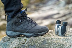 Trekking shoe and binocular closeup on a rock in the mountains during a sunny day, blurred background stock image Trekking shoe and binocular closeup on a rock in the mountains during a sunny day, blurred background stock image