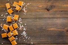 Trendy dessert. Salted caramel. Caramel cubes sprinkled by salt crystals on dark wooden background top view space for Stock Images Trendy dessert. Salted caramel. Caramel cubes sprinkled by salt crystals on dark wooden background top view space for Stock Images